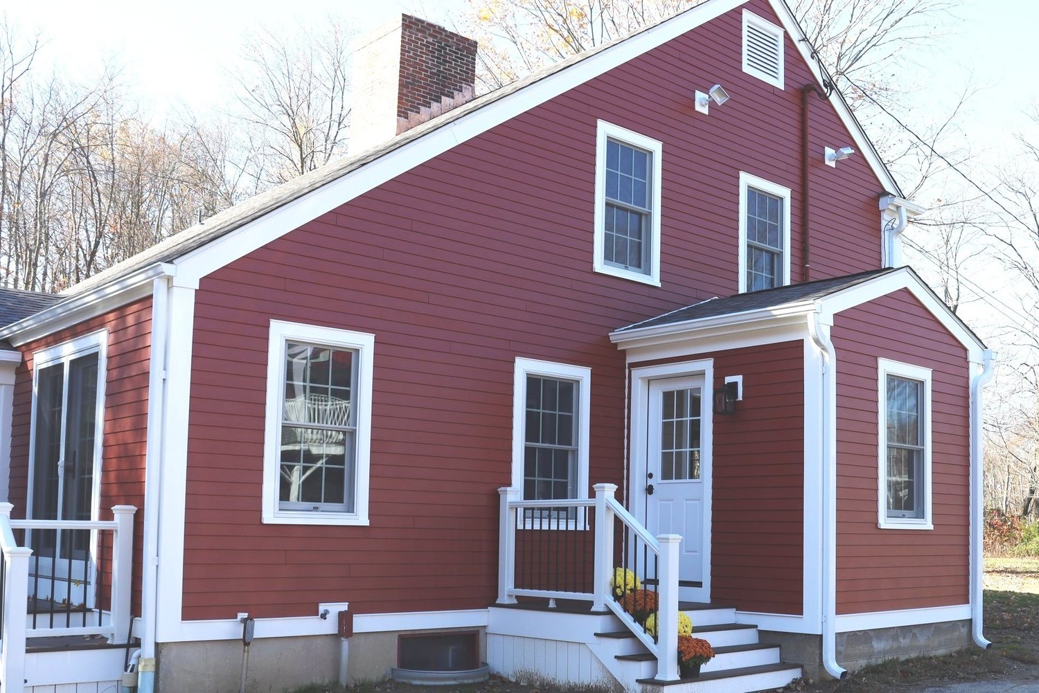 A red colonial home with a columned portico entry after a full exterior renovation