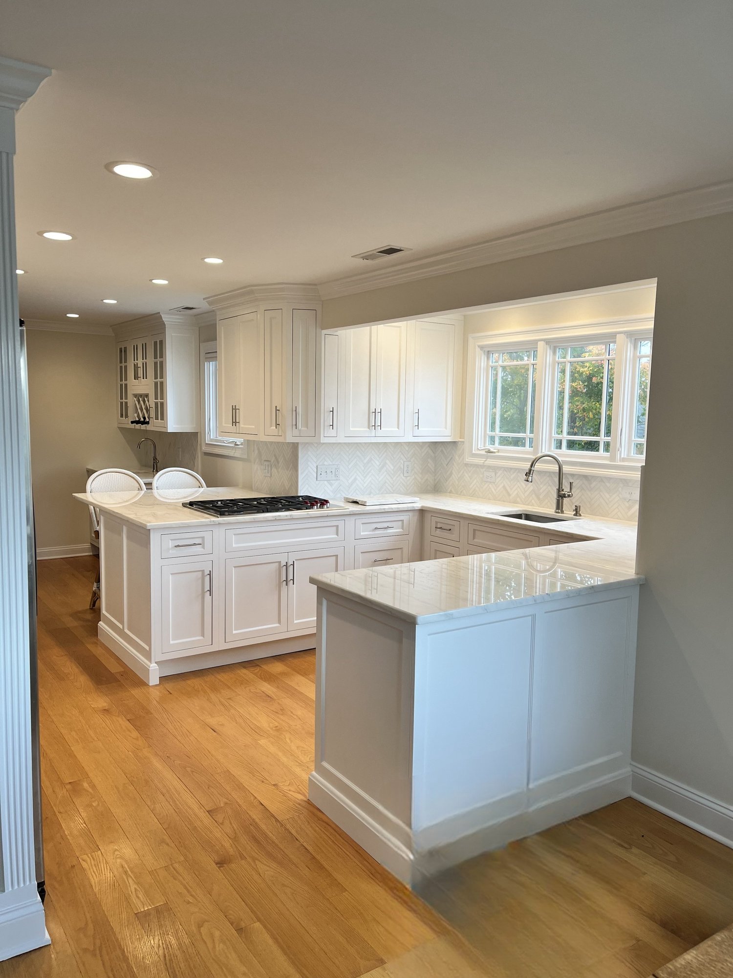 A finished white kitchen with a gas range and hardwood floors